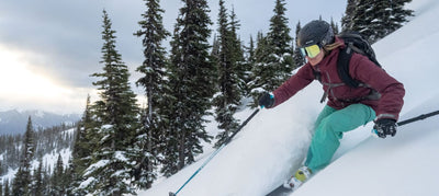 woman downhill skiing with trees in background